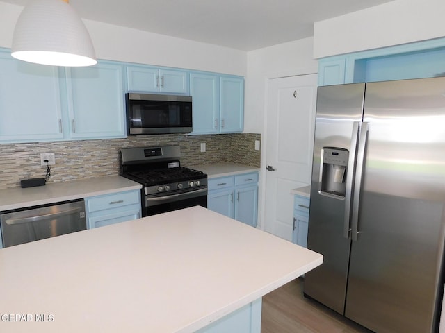 kitchen with light countertops, appliances with stainless steel finishes, tasteful backsplash, and blue cabinetry