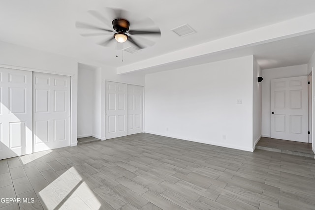 unfurnished bedroom featuring multiple closets and ceiling fan