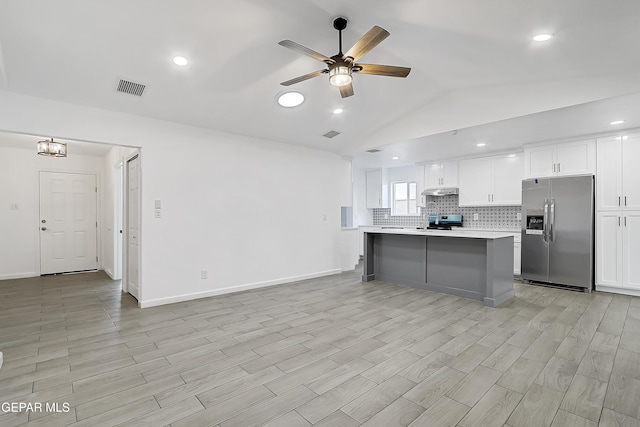 kitchen with vaulted ceiling, appliances with stainless steel finishes, white cabinetry, decorative backsplash, and a center island