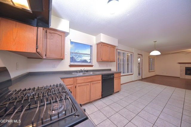 kitchen with sink, dishwasher, gas range oven, a tiled fireplace, and exhaust hood