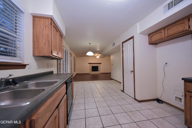 kitchen with a tile fireplace, light tile patterned flooring, black dishwasher, sink, and ceiling fan