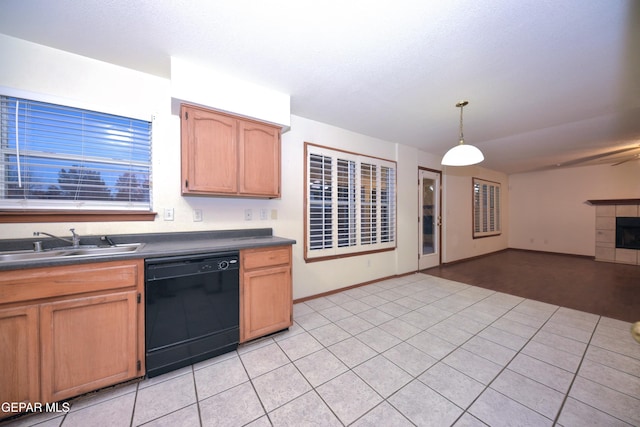 kitchen with light tile patterned flooring, black dishwasher, sink, hanging light fixtures, and a tiled fireplace