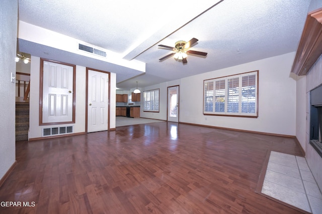 unfurnished living room featuring dark hardwood / wood-style flooring, a textured ceiling, and ceiling fan