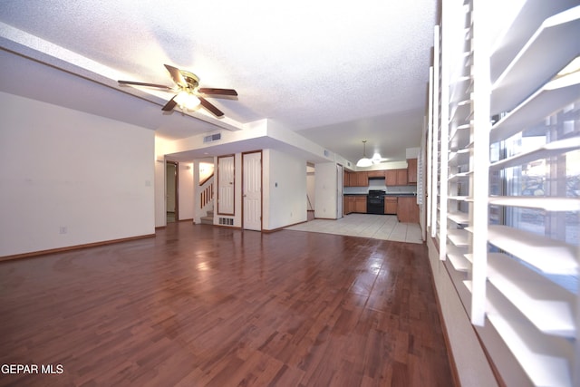 unfurnished living room featuring ceiling fan, light hardwood / wood-style floors, and a textured ceiling