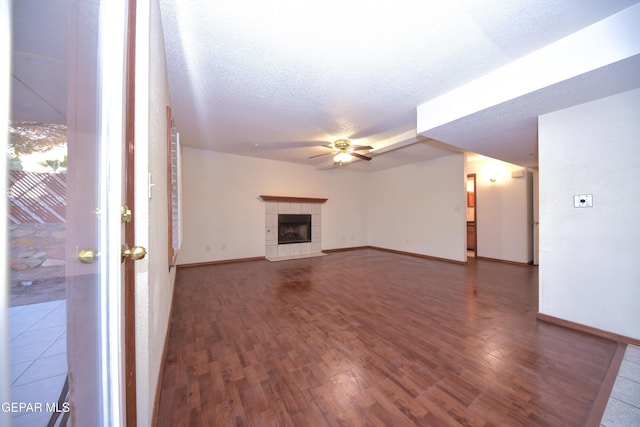 unfurnished living room featuring hardwood / wood-style flooring, ceiling fan, a fireplace, and a textured ceiling