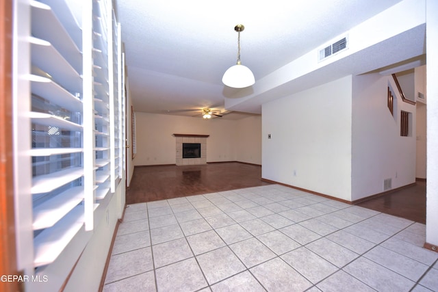 unfurnished living room with light tile patterned flooring, ceiling fan, and a tile fireplace