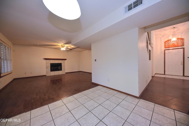 unfurnished living room featuring ceiling fan, a tiled fireplace, and light hardwood / wood-style floors