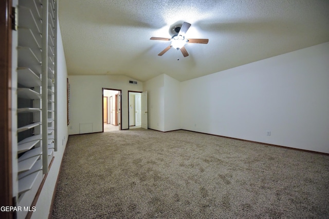 carpeted spare room featuring lofted ceiling, ceiling fan, and a textured ceiling