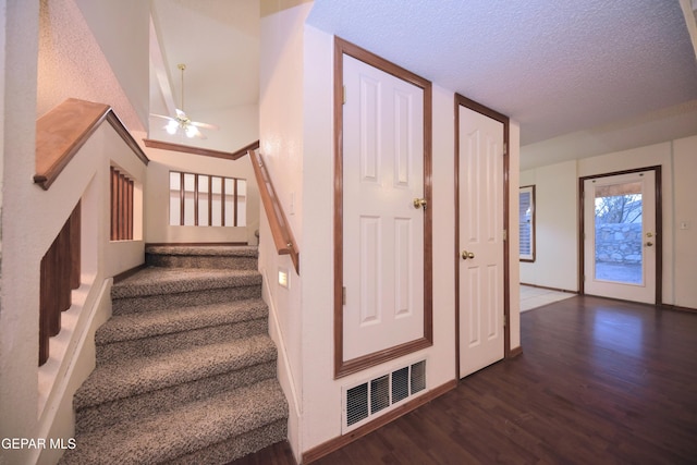 stairs with hardwood / wood-style flooring, ceiling fan, lofted ceiling, and a textured ceiling