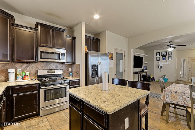 kitchen featuring a kitchen island, tasteful backsplash, a breakfast bar area, stainless steel appliances, and dark brown cabinets