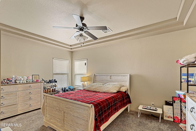 bedroom with dark colored carpet, ceiling fan, a textured ceiling, and a tray ceiling