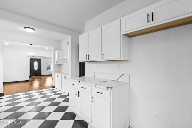 kitchen featuring pendant lighting, white cabinets, a chandelier, and light stone counters