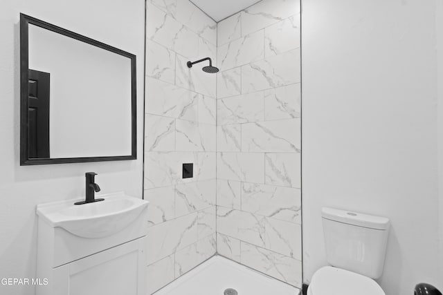 bathroom featuring vanity, toilet, and a tile shower