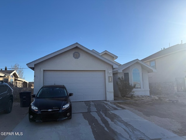 single story home featuring driveway, an attached garage, and stucco siding