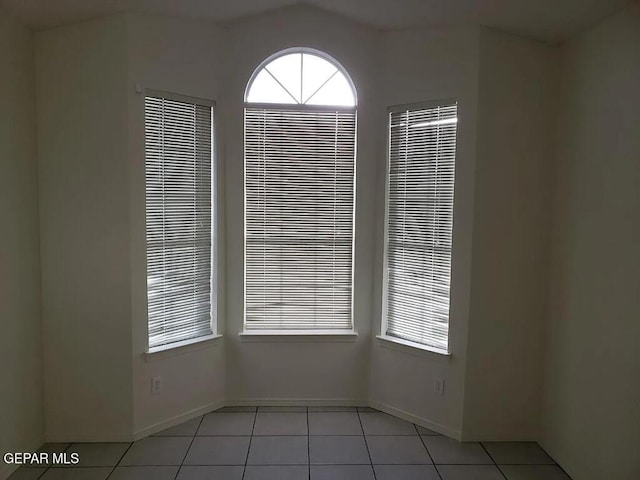 empty room featuring baseboards and light tile patterned floors