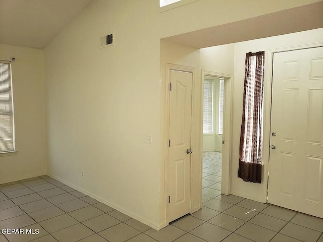 entryway featuring light tile patterned floors, vaulted ceiling, visible vents, and baseboards