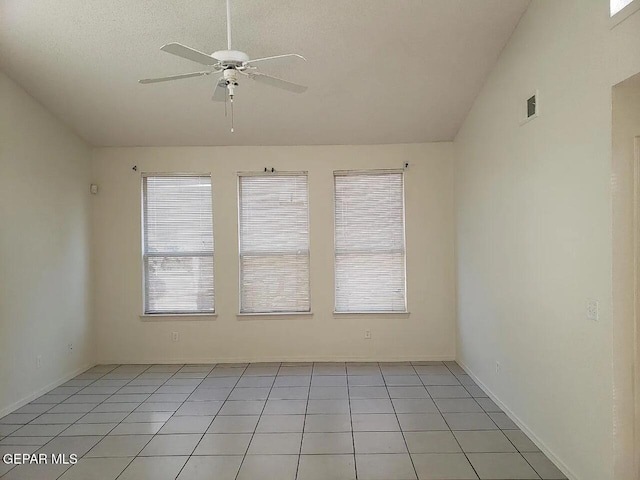 empty room featuring vaulted ceiling, light tile patterned flooring, plenty of natural light, and ceiling fan