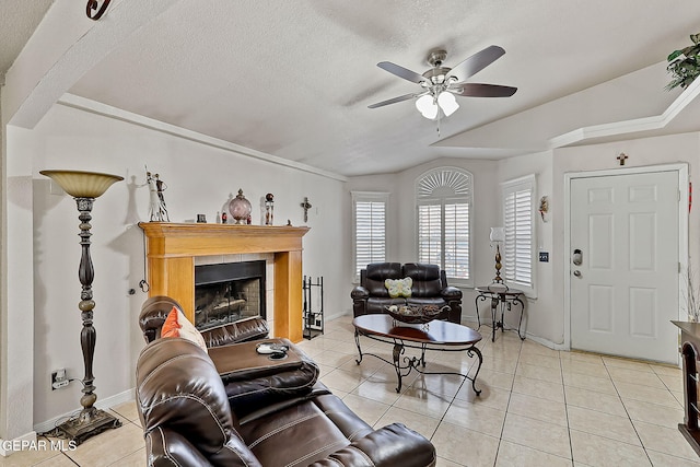 tiled living room featuring lofted ceiling, a textured ceiling, a tile fireplace, and ceiling fan