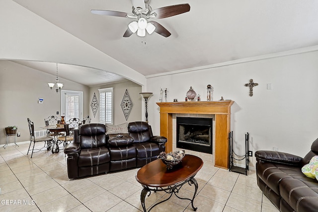 living room featuring a fireplace, ceiling fan with notable chandelier, vaulted ceiling, and light tile patterned flooring