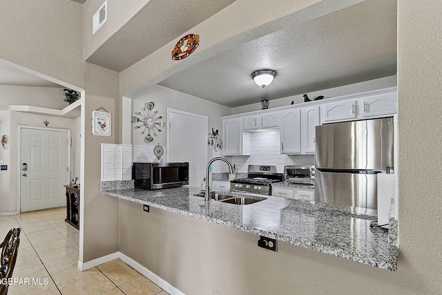 kitchen with appliances with stainless steel finishes, light stone countertops, sink, and white cabinets