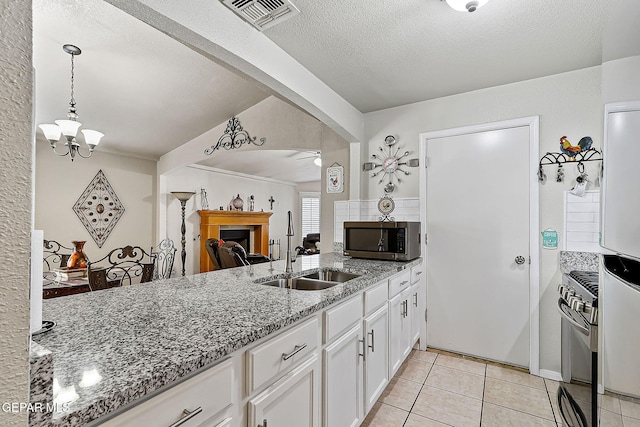 kitchen featuring sink, white cabinetry, light tile patterned floors, appliances with stainless steel finishes, and light stone countertops