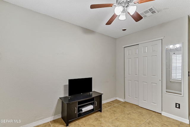 tiled bedroom with ceiling fan and a closet