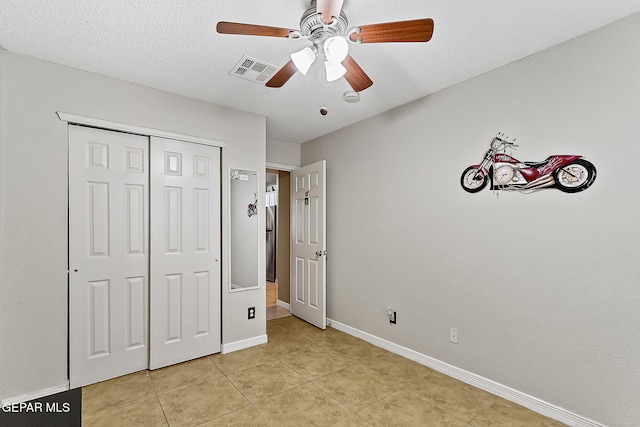 unfurnished bedroom with ceiling fan, a closet, a textured ceiling, and light tile patterned flooring