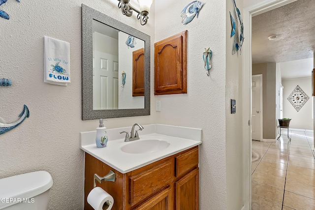 bathroom with tile patterned floors, vanity, toilet, and a textured ceiling