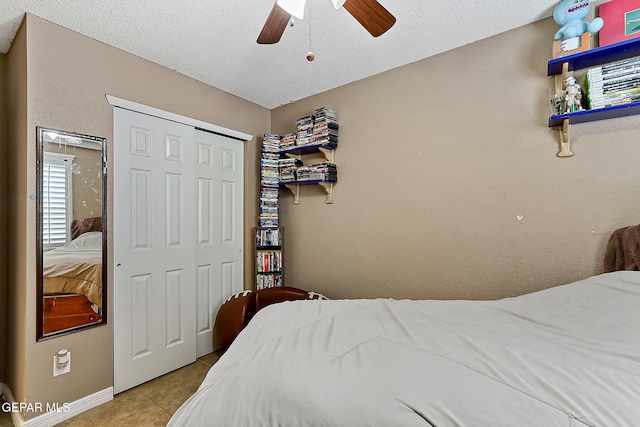 tiled bedroom with a textured ceiling, ceiling fan, and a closet