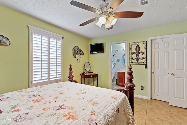 tiled bedroom featuring ceiling fan, a textured ceiling, and ensuite bath