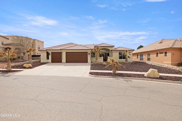 view of front of house with a tile roof, an attached garage, driveway, and stucco siding