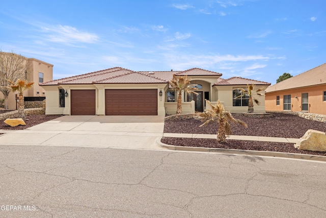 mediterranean / spanish home with concrete driveway, an attached garage, a tile roof, and stucco siding