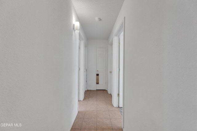 hallway featuring a textured ceiling and light tile patterned floors