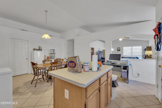 kitchen with refrigerator, lofted ceiling, a kitchen island, light tile patterned floors, and pendant lighting