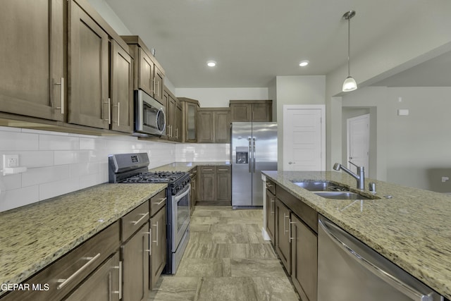 kitchen featuring light stone countertops, sink, backsplash, appliances with stainless steel finishes, and pendant lighting