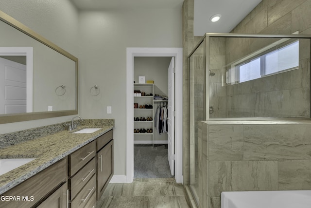 bathroom featuring a shower with door and vanity