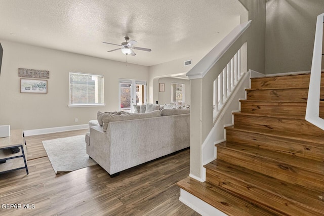 living area featuring wood finished floors, a textured ceiling, and stairs