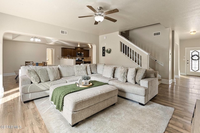 living area featuring stairs, visible vents, and wood finished floors