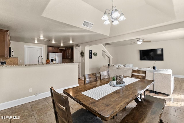 dining area featuring light tile patterned floors, baseboards, visible vents, arched walkways, and stairway