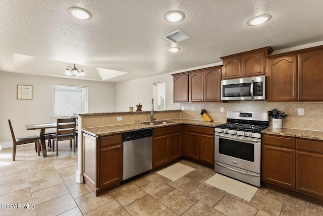 kitchen with stone counters, visible vents, backsplash, appliances with stainless steel finishes, and a sink