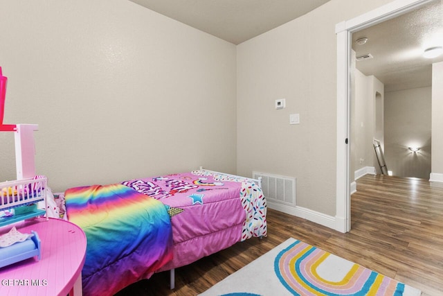 bedroom featuring visible vents, baseboards, and wood finished floors