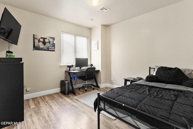 bedroom featuring baseboards, visible vents, and wood finished floors