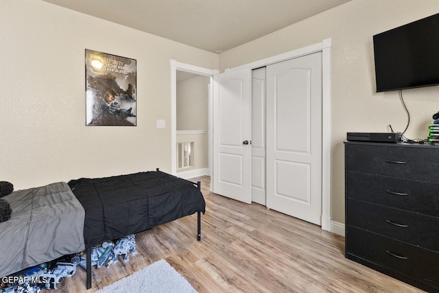 bedroom featuring light wood-style floors, baseboards, and a closet