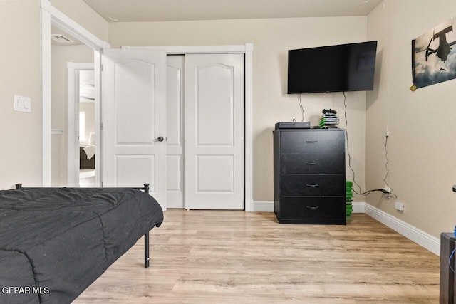 bedroom with a closet, light wood-type flooring, visible vents, and baseboards