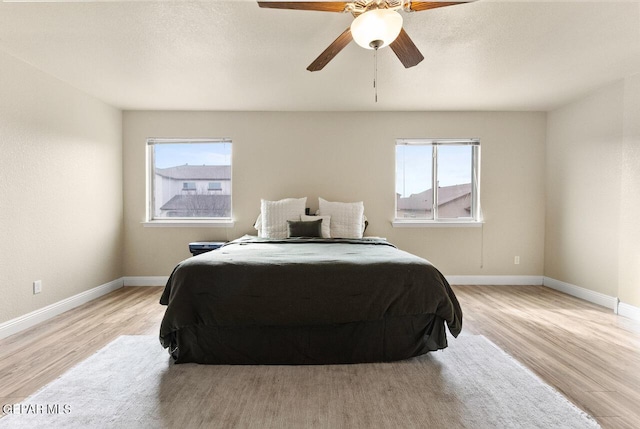 bedroom with light wood finished floors, multiple windows, and baseboards