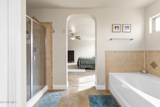 bathroom featuring baseboards, a ceiling fan, connected bathroom, a shower stall, and a bath