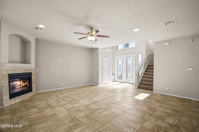 unfurnished living room with a textured ceiling, french doors, a tile fireplace, and ceiling fan