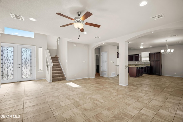 unfurnished living room with ceiling fan with notable chandelier and french doors