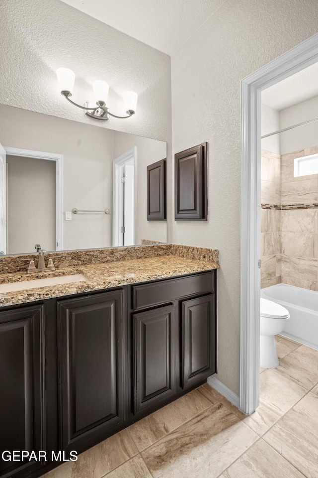 full bathroom with a textured ceiling, toilet, vanity, and tiled shower / bath combo