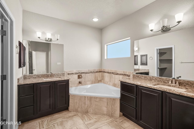 bathroom featuring a notable chandelier, vanity, and a relaxing tiled tub